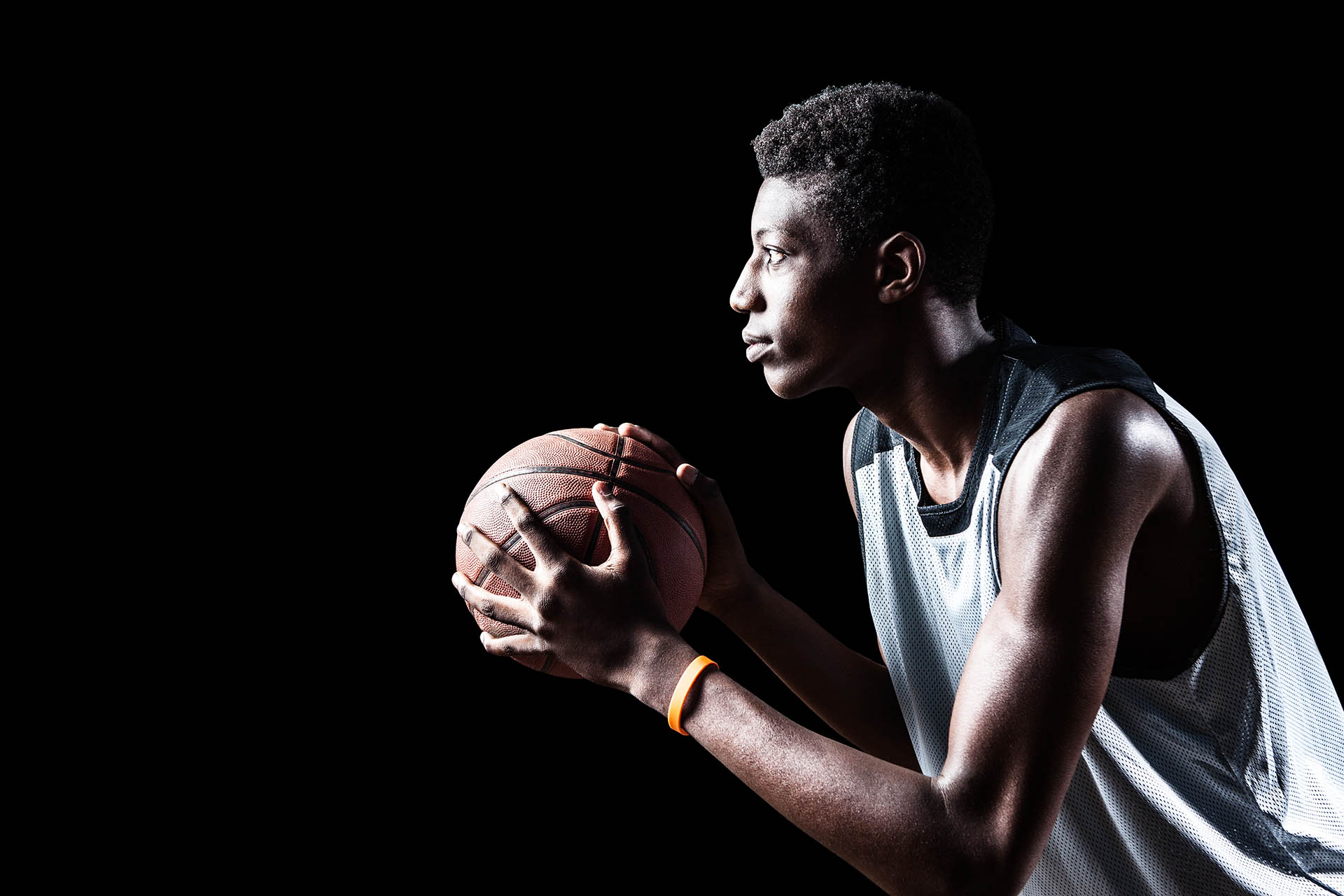Young basketball player isolated on black background